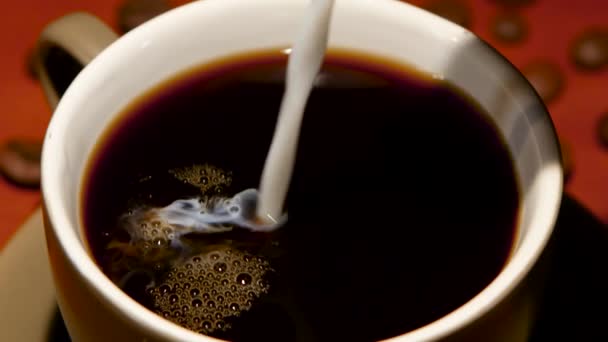 Dans une tasse avec du café noir chaud a ajouté beaucoup de lait. Gros plan 