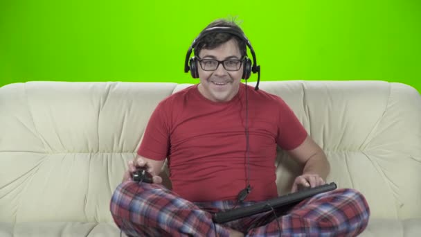 Hombre jugando juego de ordenador sentado en casa en el sofá — Vídeos de Stock