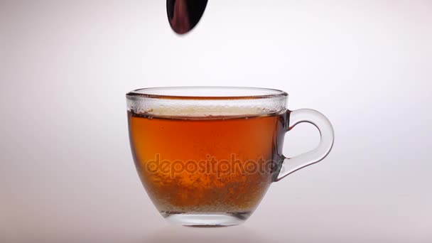 Mélanger le sucre dans une tasse en verre avec le thé d'une cuillère 