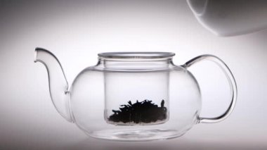 Çay yaprakları ile şeffaf çaydanlık içine kaynar su dökülür