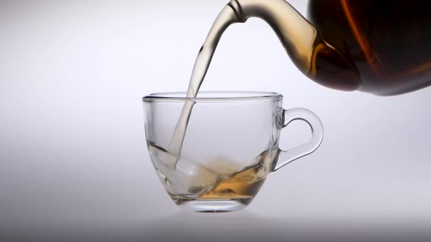 Tea is poured from a teapot into transparent glass cup — Stock Video