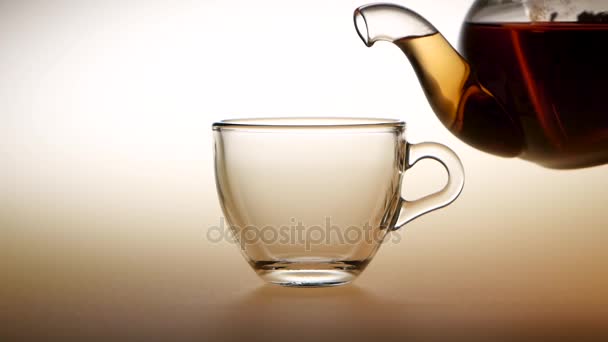 Tea is poured from teapot into glass cup. Slow motion — Stock Video