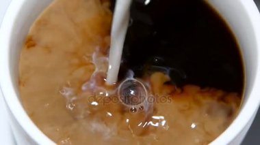 Siyah kahve fincan içinde krema dökülür. Ağır çekim