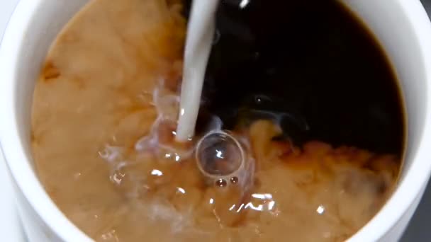 Siyah kahve fincan içinde krema dökülür. Ağır çekim — Stok video