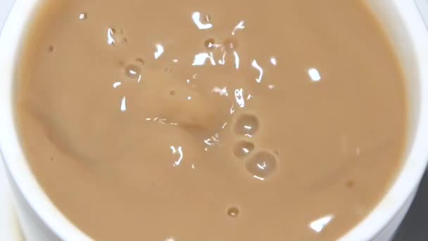 V šálku kávy s mlékem kapky kus cukru — Stock video