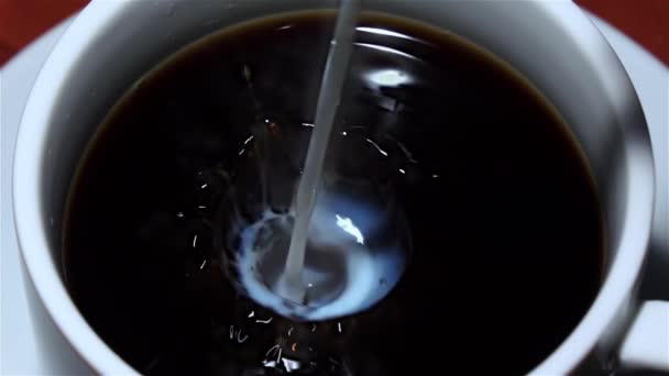 Dans une tasse de café noir versé du lait. Vue de dessus. Gros plan 