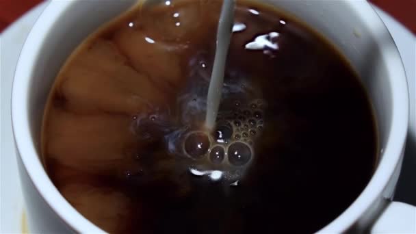 Mleko jest dodane do czarnej kawy. Widok z góry. Zwolnionym tempie — Wideo stockowe