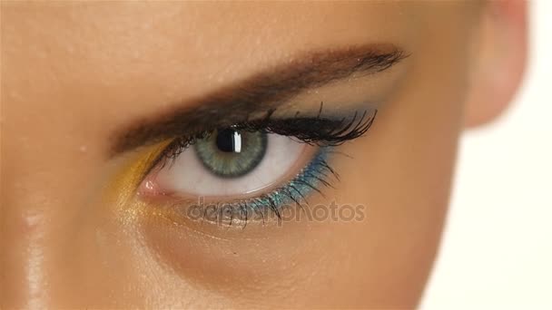 Chica con ojos grises con hermoso maquillaje y un ojo agudo mirando hacia arriba. De cerca. — Vídeos de Stock