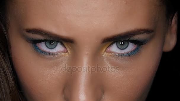 Κορίτσι με ένα όμορφο φωτεινό μακιγιάζ και αιχμηρά μάτια αναζητώντας με προσήλωση. Κοντινό πλάνο. Αργή κίνηση — Αρχείο Βίντεο