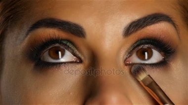 Kız make up seyir ile visagiste fırça yukarıya onun yapmak ayarlar. Yakın çekim. Ağır çekim