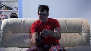 Gözlüklü adam kanepede otururken bilgisayar oyunu oynamak