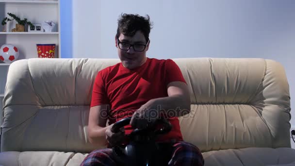 Мужчина играет в домашние онлайн-игры с помощью рулевого колеса — стоковое видео