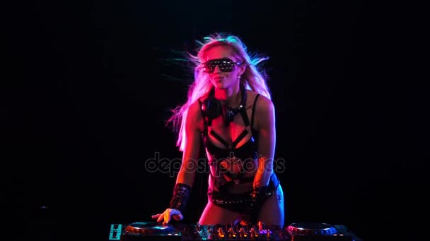 Sexy DJ rubia mujer en luz de neón detrás de las cubiertas — Vídeos de Stock