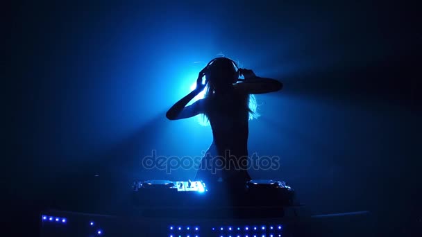 Сексуальна дівчина DJ грає трек у синьому світлі — стокове відео