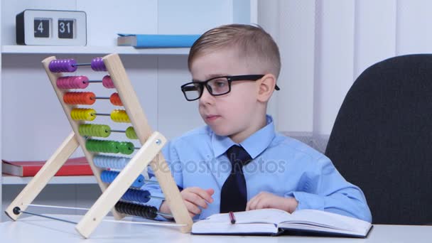 Дитячий хлопчик в окулярах розглядає рахунки і пише в блокноті — стокове відео