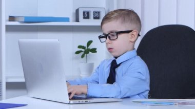 Parlak çocuk bir dizüstü bilgisayarda yazarak ve kendisi için yaprak yazar