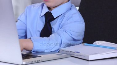 Dizüstü bilgisayar ve tablolar yazarak klavye bakarak küçük çocuk işadamı