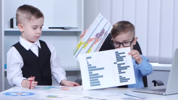 Двоє маленьких хлопчиків бізнесмен в офісі розглядають графіки і графіки — стокове відео