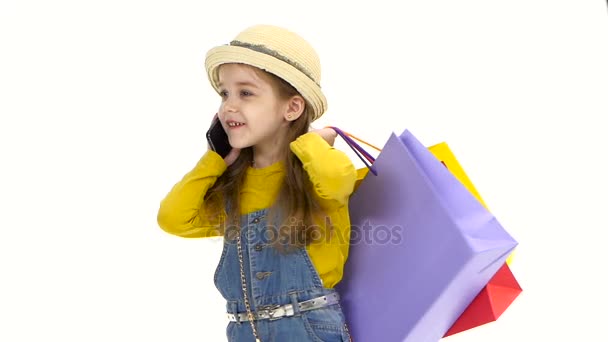 Девочка держит сумки, разговаривает по телефону, улыбается. Белый фон. Медленное движение — стоковое видео