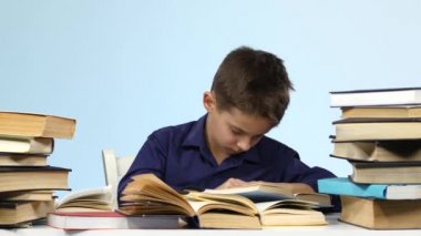 Çocuk masada oturur ve bir kitap için uykuya dalar. Mavi arka plan