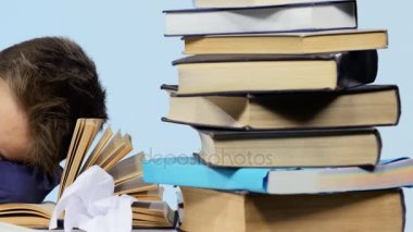 Yorgun çocuk kitapları arasında masa başında uykuya daldı. Mavi arka plan