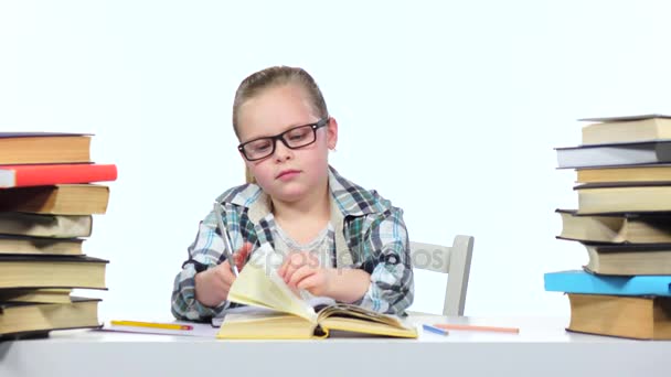 Flickan sitter vid bordet bläddrade igenom boken. Vit bakgrund — Stockvideo