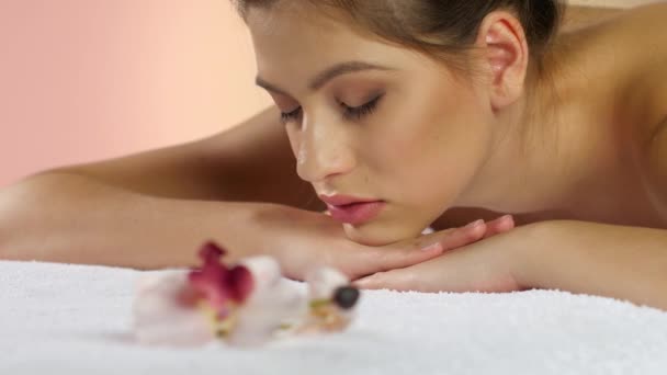 Flicka slappnar av efter en massage liggande på vita handdukar. Studio — Stockvideo