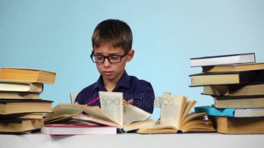 Küçük çocuk bir not defterinde yazıyor ve o değil gibi. Mavi arka plan. Ağır çekim
