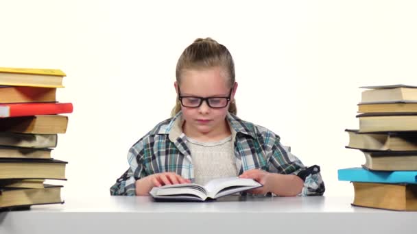 Girl chooses a book and starts to read it. White background — Stock Video