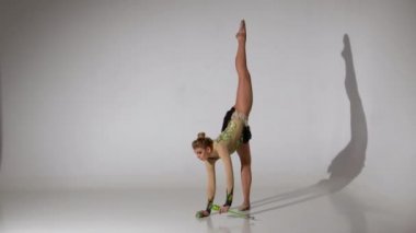 Jimnastikçi geri döndürür yapıyor ve tek ayak üstünde duruyor. Beyaz arka plan