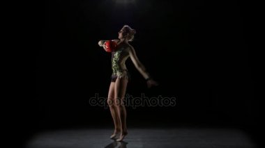 Esnek jimnastikçi top onun vücudunda götürür. Siyah arka plan