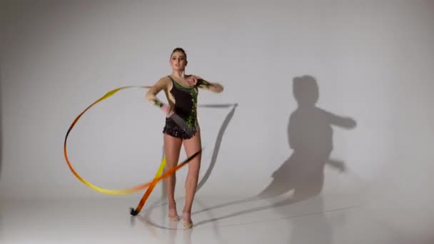 Gymnast gracefully move with a ribbon in his hands. White background — Stock Video