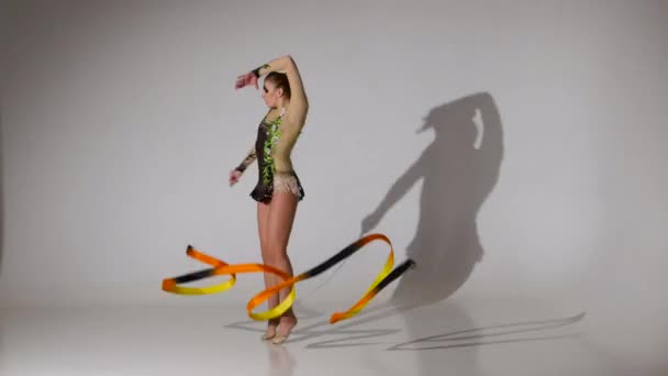 Dělat akrobatické gymnastice se pohybuje s pásky. Bílé pozadí — Stock video
