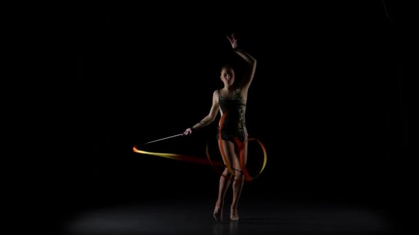 Gymnast gracefully move with a ribbon in his hands. Black background — Stock Video