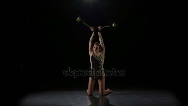 Rhythmische Sportgymnastin wirft Keule hoch und fängt sie ein. schwarzer Hintergrund — Stockvideo