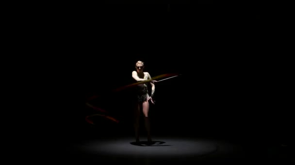 Flexibilní gymnastka s páskou vytváří krásné ruce ladnými pohyby. Černé pozadí — Stock video