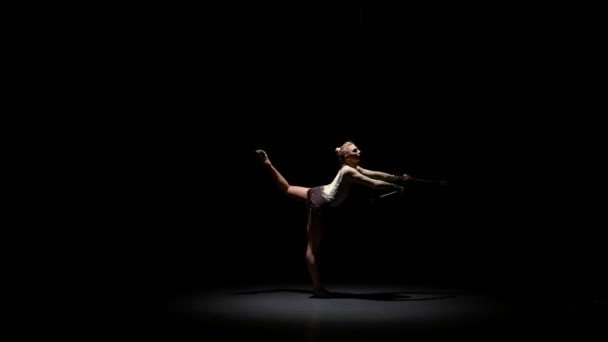 Rhythmic gymnast throws mace up and catches her. Black background — Stock Video