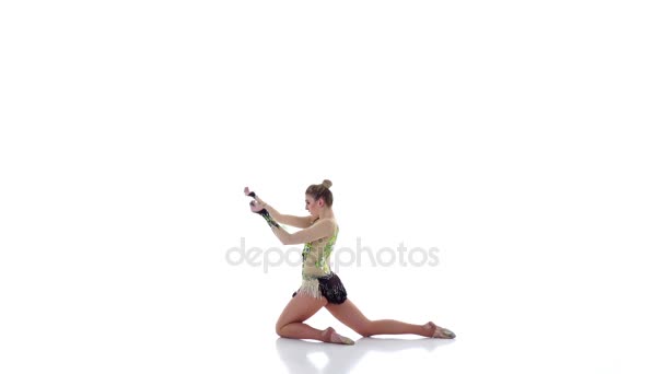 Девушка гимнастка с булавой в руке вращается вокруг него. Белый фон. Медленное движение — стоковое видео