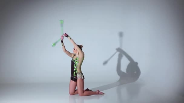 Girl gymnast doing acrobatic movement with a mace in his hand. White background. Slow motion — Stock Video