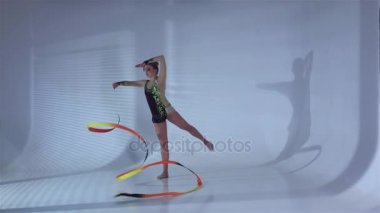 Onun elinde bir kurdele ile incelikle dans ritmik jimnastikçi. Beyaz arka plan. Ağır çekim