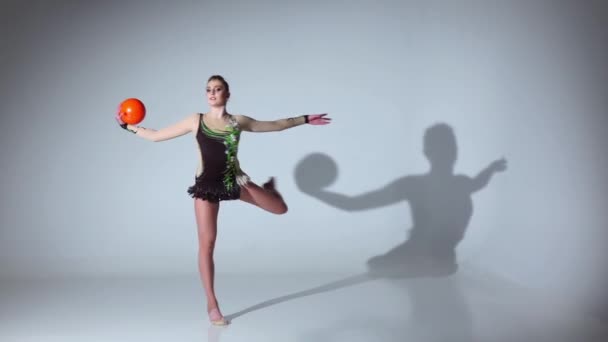 Gymnast med bollen i händerna gör akrobatiska flyttar. Vit bakgrund. Slow motion — Stockvideo