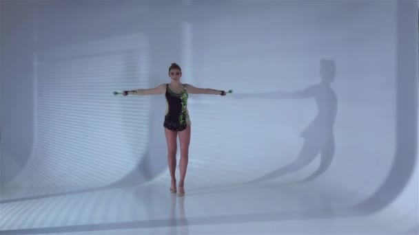 Lány tornász csinál akrobatikus mozgalom-val a kezében egy buzogányt. Fehér háttér. Lassú mozgás — Stock videók