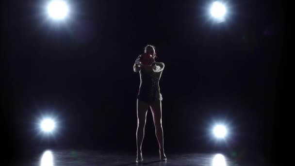 Gimnasta con la pelota en sus manos haciendo movimientos acrobáticos. Fondo negro. Luz trasera. Movimiento lento — Vídeos de Stock