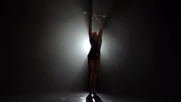 Gymnast in a nice suit with a mace. Black background. Slow motion. Silhouette — Stock Video