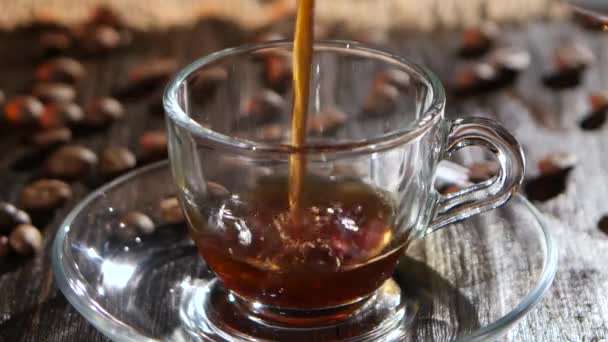 Černá káva se nalije do skla průhledného kelímku na talíř — Stock video