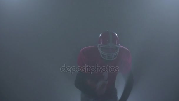 American football player runs on the camera. Smoky background studio — Stock Video