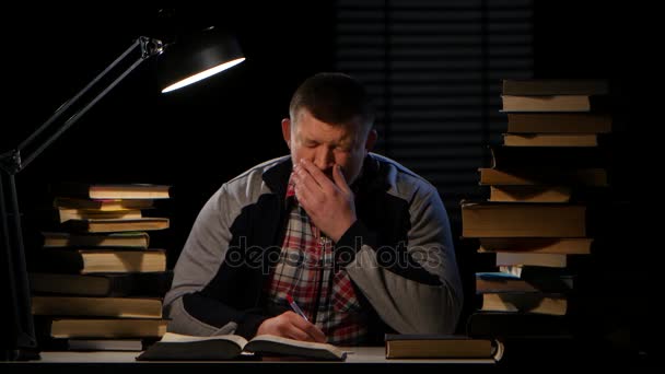 Boy reads the book and falls asleep in the lamplight. Black background — Stock Video