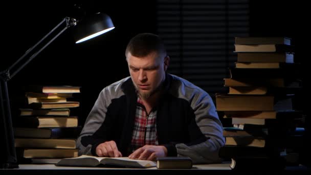 Muž sedí u stolu, čtení, hledání informací a šťastný. Černé pozadí — Stock video