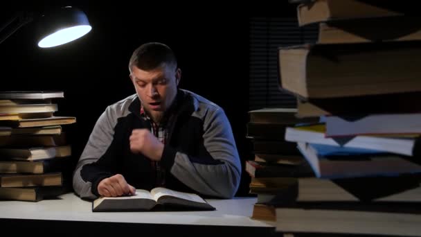 Homem folheando o livro, ele está com sono e cansado. Fundo preto — Vídeo de Stock