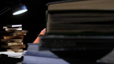 Kız bir kitap aracılığıyla leafing ve masada uykuya dalmak. Siyah arka plan